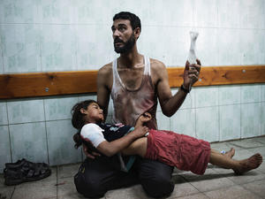 A Palestinian man holds a girl injured during shelling at a U.N.-run school sheltering Palestinians, at a hospital in the northern Gaza Strip on July 24, 2014.